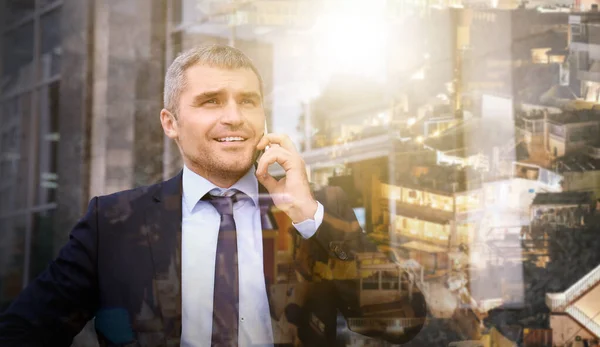 Doble exposición de hombre de negocios maduro hablando por teléfono móvil y ciudad moderna — Foto de Stock