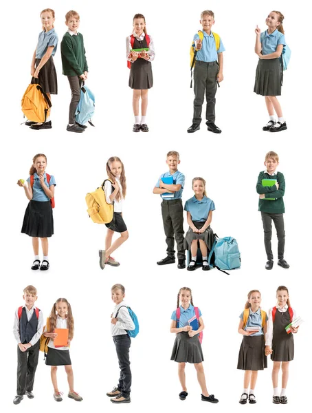 Colagem com pequenos alunos bonitos em diferentes uniformes escolares em fundo branco — Fotografia de Stock