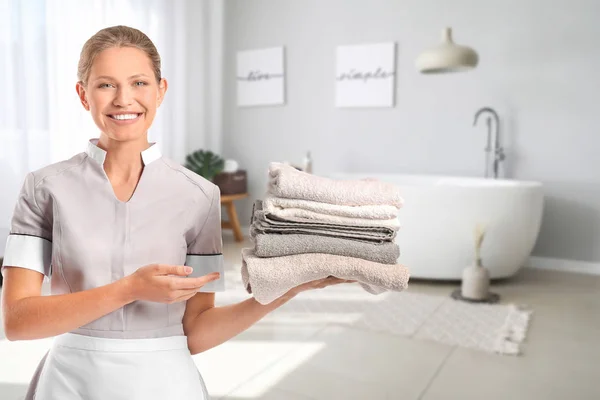 Portrait of beautiful female housekeeper with clean towels in bathroom — Stock Photo, Image
