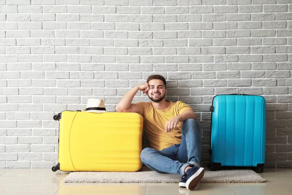 Young male tourist with luggage near brick wall — Stock Photo, Image