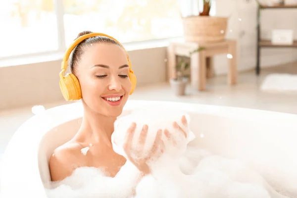 Schöne junge Frau mit Kopfhörern entspannt in der Badewanne — Stockfoto