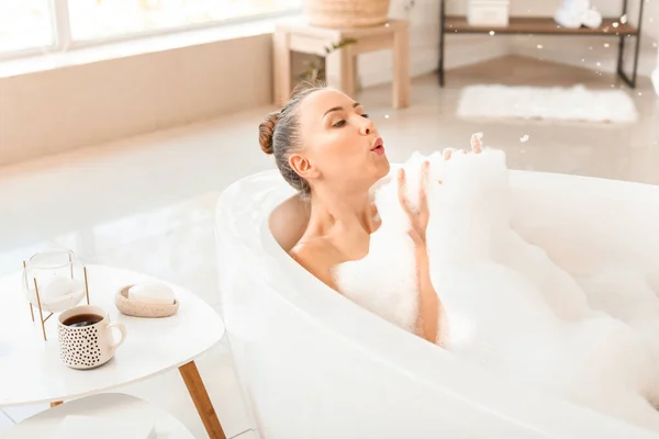 Jovem bonita brincando com espuma na banheira — Fotografia de Stock