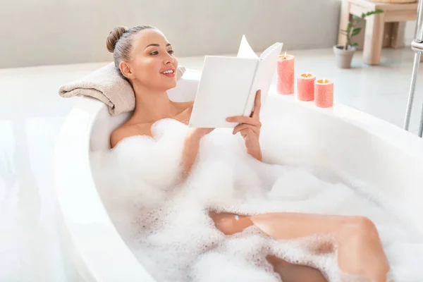 Beautiful young woman reading book in bathtub — Stock Photo, Image