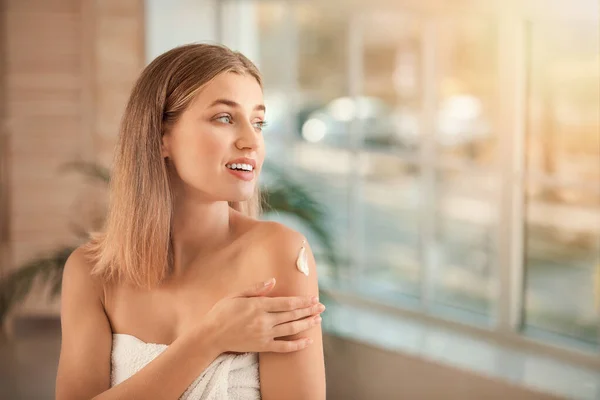 Hermosa mujer joven aplicando crema en su hombro en el baño —  Fotos de Stock