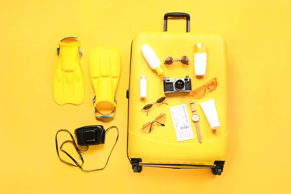 Suitcase with travel accessories on color background — Stock Photo, Image