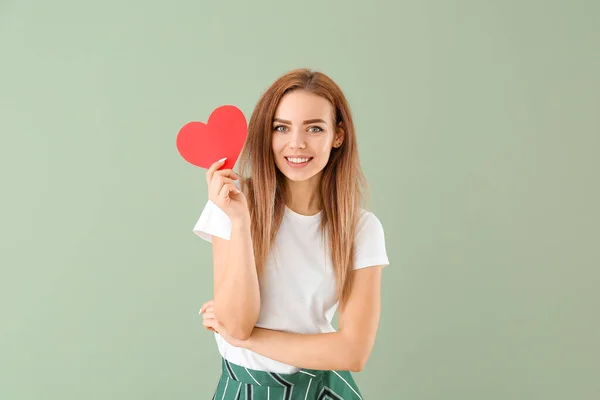 Beautiful young woman with  red heart on color background — Stock Photo, Image