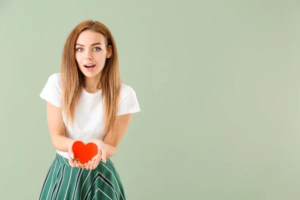 Beautiful young woman with  red heart on color background — Stock Photo, Image