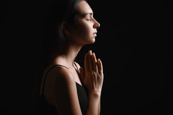 Siluet berdoa wanita muda di latar belakang gelap — Stok Foto