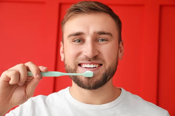Красивий чоловік з зубною щіткою на кольоровому фоні — стокове фото