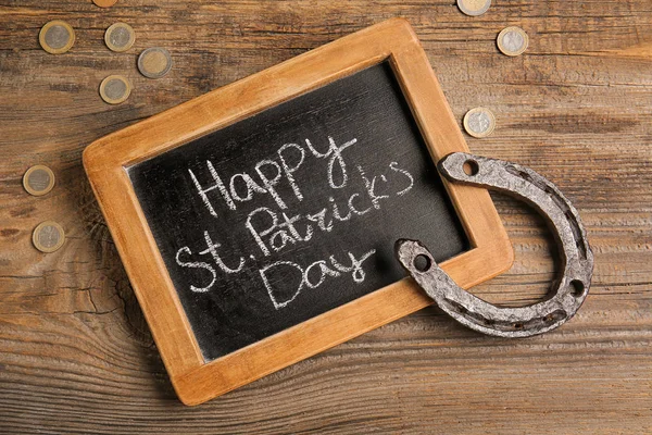 Horseshoe and chalkboard with text HAPPY ST. PATRICK 'S DAY on wooden background — стоковое фото