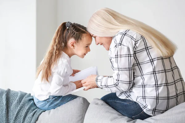Klein meisje en grootmoeder lezen samen boek thuis — Stockfoto