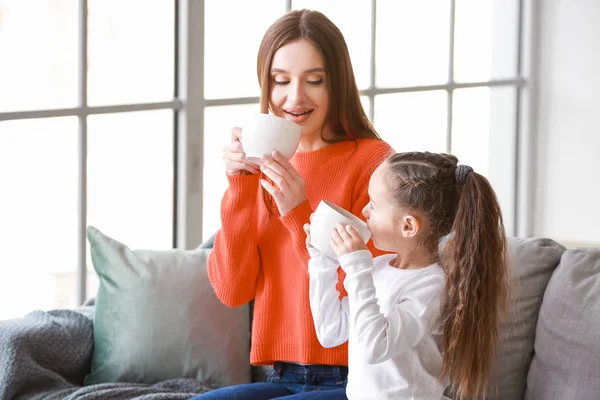 Молода жінка зі своєю маленькою донькою п'є чай разом вдома — стокове фото