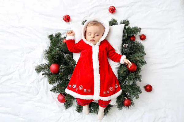 Bebê bonito em traje de Papai Noel e com decoração de Natal deitado na cama, vista superior — Fotografia de Stock