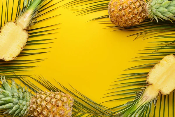 Piñas frescas maduras y hojas tropicales sobre fondo de color — Foto de Stock