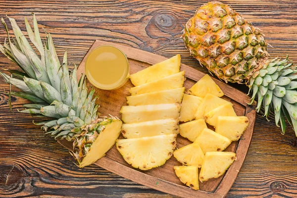 Fresh ripe pineapples and juice on wooden background — Stock Photo, Image