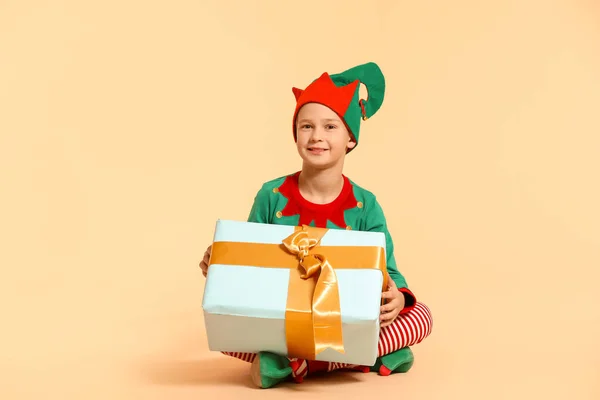 Malý chlapec v kostýmu elfa a s dárkem na barevném pozadí — Stock fotografie