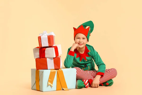 Kleiner Junge im Elfenkostüm und mit Geschenken auf farbigem Hintergrund — Stockfoto