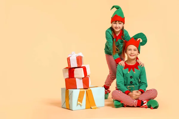 Små barn i kostym nisse och med gåvor på färg bakgrund — Stockfoto
