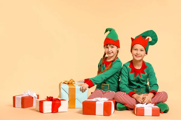 Kleine Kinder im Elfenkostüm und mit Geschenken auf farbigem Hintergrund — Stockfoto