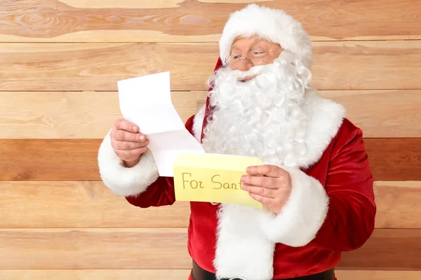 Santa Claus con carta sobre fondo de madera — Foto de Stock