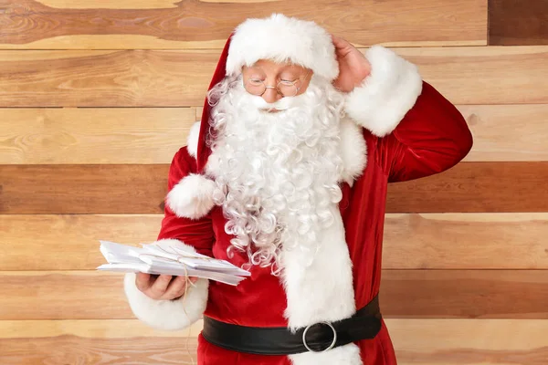 Санта-Клаус с письмами на деревянном фоне — стоковое фото