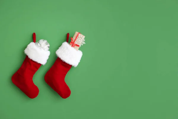 Karácsonyi zokni ajándékokkal lógó színes falon — Stock Fotó