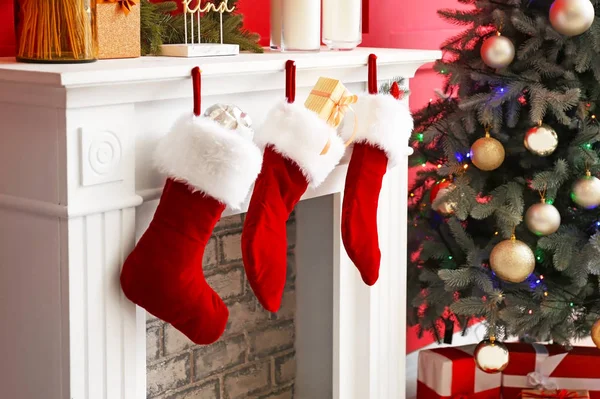 Weihnachtssocken mit Geschenken hängen am Kamin im Zimmer — Stockfoto