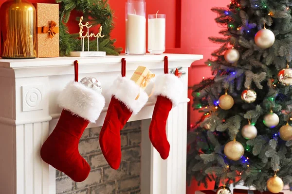 Christmas socks with gifts hanging on fireplace in room — Stock Photo, Image