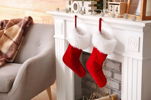 Christmas socks with gifts hanging on fireplace in room — Stock Photo, Image