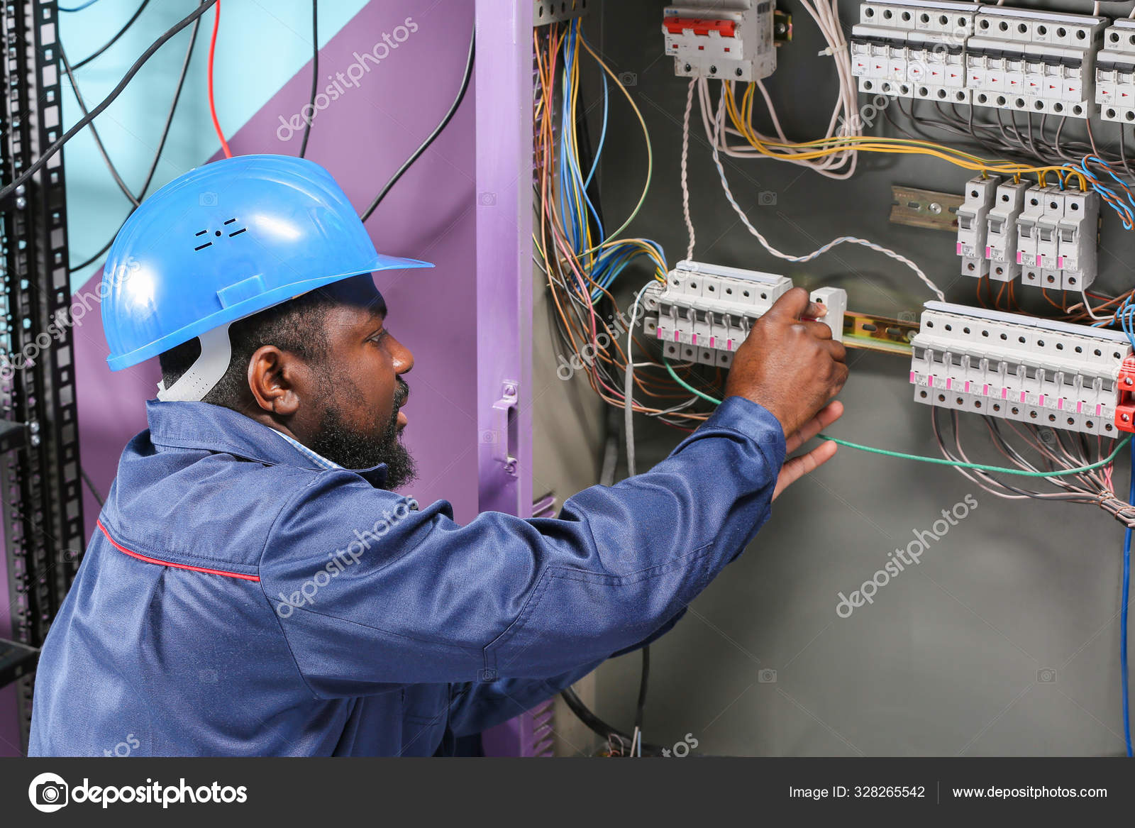 African American electrician performing wiring in distribution board African American electrician performing wiring in distribution board