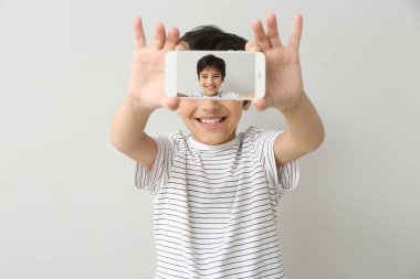 Küçük çocuk arka planda selfie çekiyor.