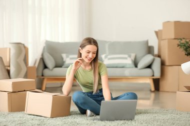 Yeni evinin dizaynını dizüstü bilgisayarla planlayan mutlu genç bir kadın.