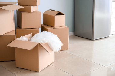 Taşındığı gün yeni dairenin mutfağında içinde eşyalar ve buzdolabı olan karton kutular.