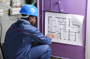 Afro-Amerikalı elektrikçi dağıtım panosunda elektrik tesisatı yapıyor.