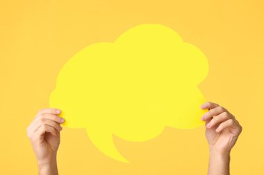 Female hands with blank speech bubble on color background