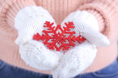 Woman with knitted mittens and snowflake, closeup