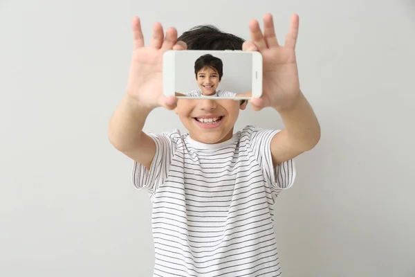 Liten pojke som tar selfie på ljus bakgrund — Stockfoto