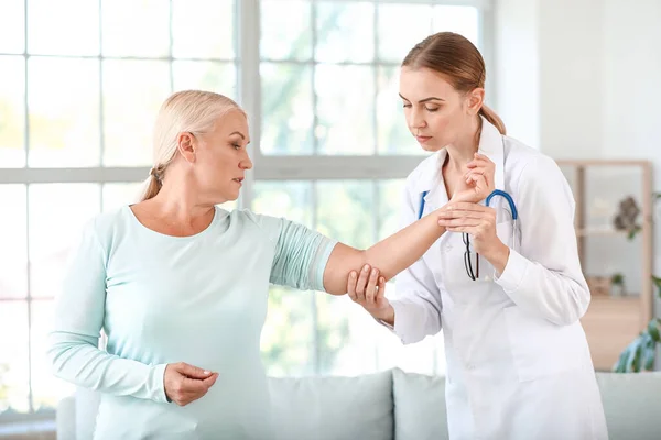 Médecin examinant femme mature avec des douleurs articulaires à la maison — Photo