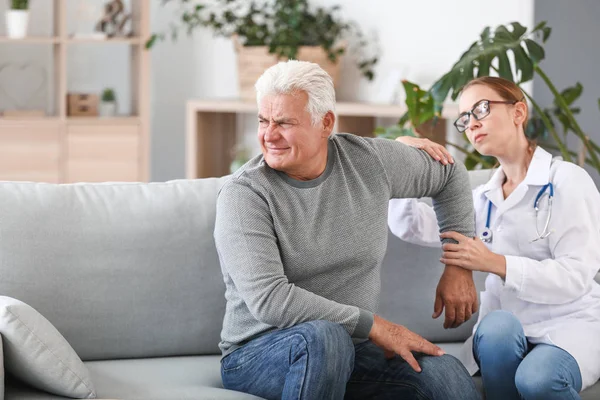 Dokter onderzoeken volwassen man met gewrichtspijn thuis — Stockfoto