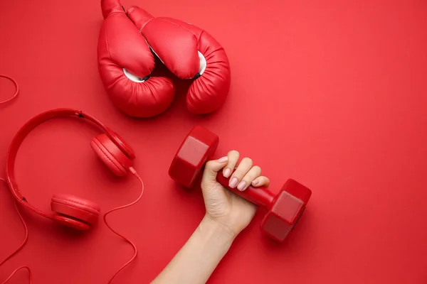 Mano femenina con mancuerna, guantes de boxeo y auriculares sobre fondo de color — Foto de Stock