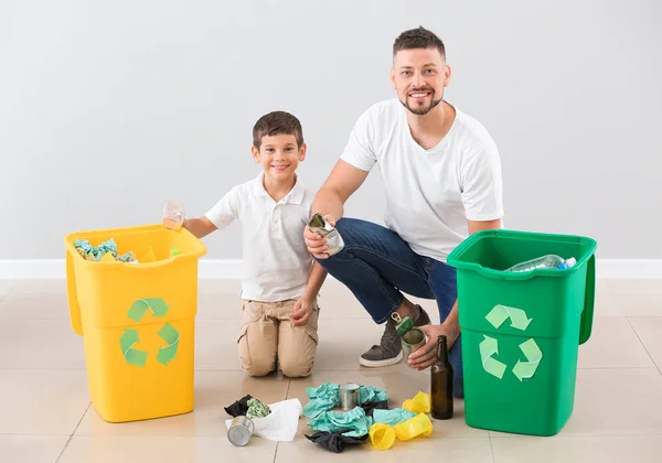 Padre e hijo con contenedores para basura sobre fondo claro. Concepto de reciclaje — Foto de Stock