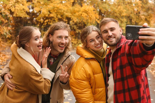 Gelukkige jonge vrienden nemen selfie in de herfst park — Stockfoto
