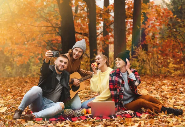 Jovens amigos felizes tomando selfie no parque de outono — Fotografia de Stock