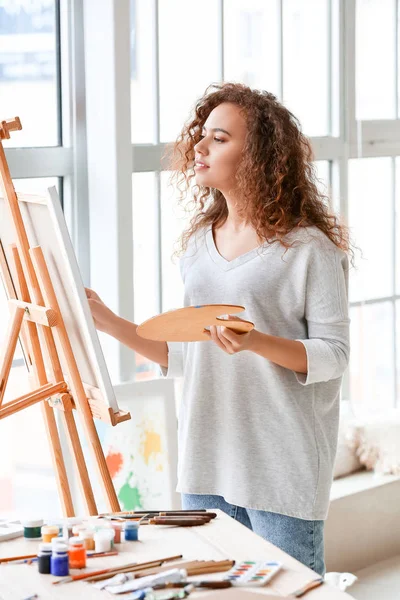 Beautiful female African-American artist painting in studio — Stock Photo, Image