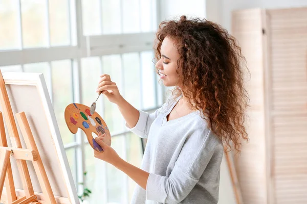 Beautiful female African-American artist painting in studio — Stock Photo, Image