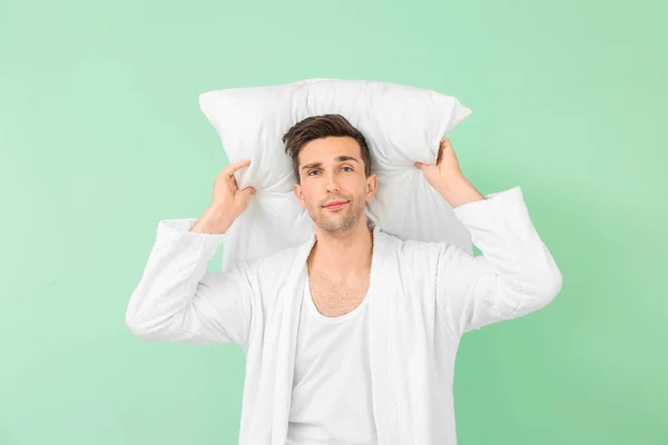 Handsome man in bathrobe and with pillow on color background — Stock Photo, Image