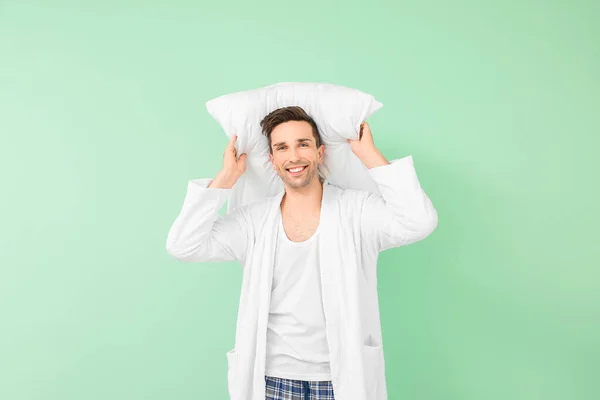 Handsome man in bathrobe and with pillow on color background — Stock Photo, Image