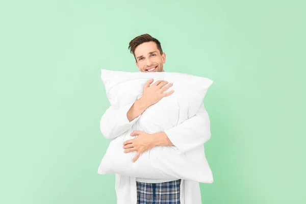 Handsome man in bathrobe and with pillow on color background — Stock Photo, Image