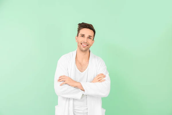 Handsome man in bathrobe on color background — Stock Photo, Image