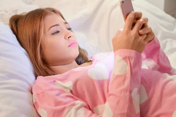 Дівчина-підліток з мобільним телефоном лежить в ліжку вночі — стокове фото